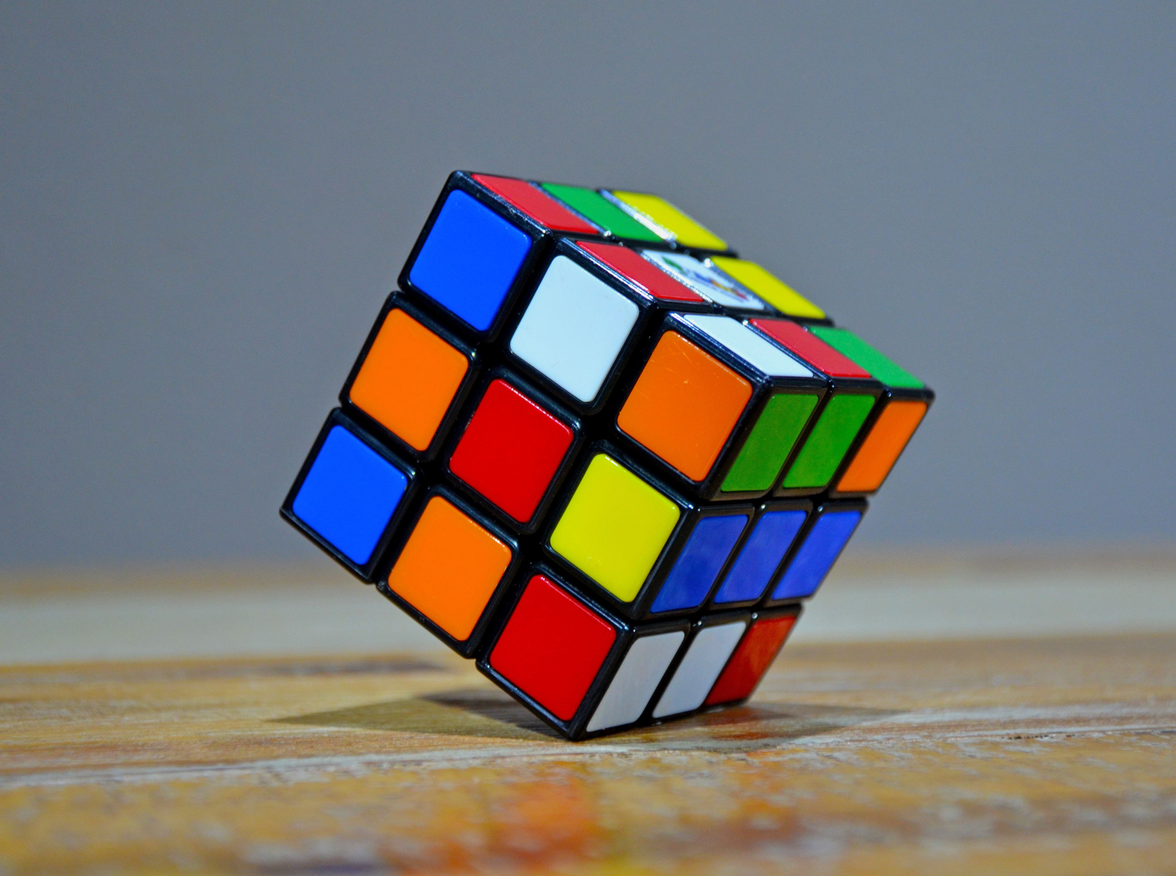 Close-up of a classic 3x3 Rubik's Cube tilted on a wooden surface, showing all six colors